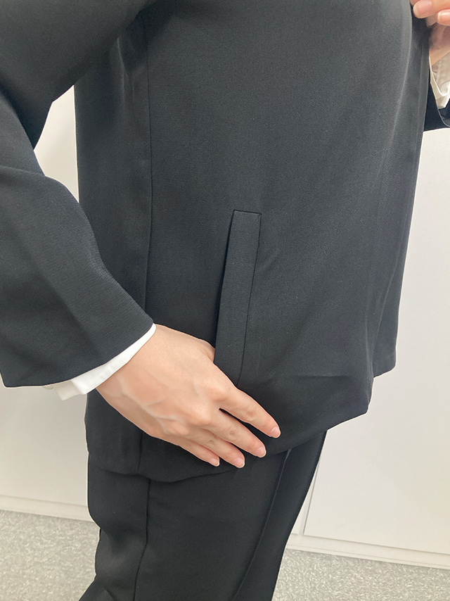 身長164cmスタッフKが着用するノーカラージャケット＆ストレートパンツセットアップスーツ(ブラック)のディティール ジャケットのポケットアップ画像